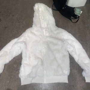Vit teddyjacka med huva - Mysig vit teddyjacka med huva och dragkedja framtill.