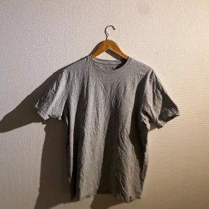 Grå t-shirt från pull & bear - En klassisk grå t-shirt i bomull. Perfekt för en avslappnad stil. Den har en rund hals och korta ärmar.