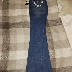 Blå jeans från True Religion - Snygga blå jeans från True Religion med broderade detaljer på bakfickorna. Dom är låga och flare ben. Modellen heter Joey LR Flare färgen är Diamond valley st 27 oanvända med lapparna kvar 