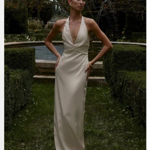 Krämvit långklänning från NAKD - Drömmig långklänning i satin från NAKD, som är helt slutsåld på hemsidan. Perfekt till balen!! Storlek 36 och jag är 165cm lång för referens💕💕 Endast testad en gång så prislappen sitter kvar. Säljer då jag hittade en annan klänning🙏🏻