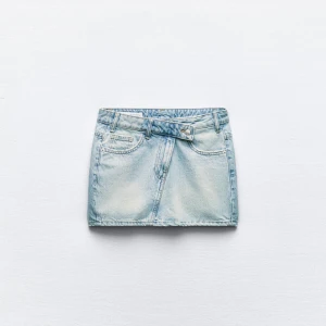 Blå jeanskjol från Zara - Trendig blå jeanskjol från Zara i kort modell. Kjolen har klassiska femficksdetaljer och en knappgylf. Aldrig använd och prislapp kvar. Slut i de flesta storlekarna på hemsidan💕