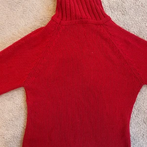 Röd stickad polotröja - Snygg röd stickad polotröja med långa ärmar. Perfekt för kyliga dagar med sin mysiga och varma design. Polokragen ger extra värme och stil.