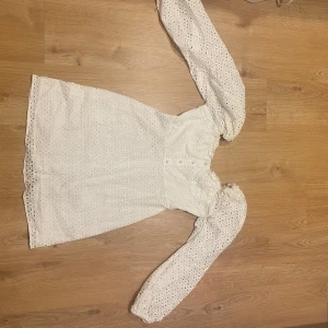En vitkort klänning (studenten) - En kort vit klänning med broderie anglaise som har långa ärmar. materialet är bomull och i storlek 38 euro. klänningen är väldigt bekväm och jag har använt den en gång för min studenter 2024. klänningen är i bra kvalitet och har inga skador eller smuts alls. Det går jätte bra att prova och kolla om klänningen passar!! Skriv bara till mig :)