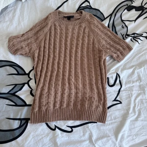 Beige stickad tröja - Säljer en beige stickad tröja från MyWearWoman i storlek S. Tröjan har ett snyggt flätmönster och korta ärmar, perfekt för lager-på-lager eller som den är. Ribbstickade kanter.