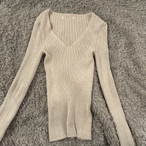 Beige ribbad tröja - Snygg beige ribbad tröja med v-ringning och långa ärmar. Perfekt för en stilren look och passar bra till både jeans och kjol. Ett måste i garderoben för den som gillar enkel och elegant stil. Ger än en fitted look. 💞