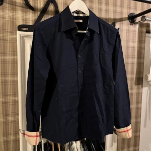 Mörkblå skjorta från Burberry - Snygg mörkblå skjorta från Burberry köpt nyligen aldrig använd!, säljs pågrund av för liten storlek, köpt av luxurio secret AB på Instagram, pris går att diskuteras vid snabb affär, för fler bilder eller funderingar hör av er!