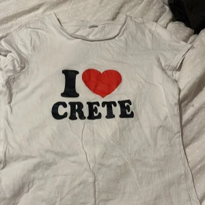 Vit t-shirt med tryck - Säljer en vit t-shirt med texten 'I ❤️ CRETE' i svart och rött. Köpte i Grekland 