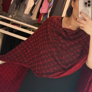 Röd sjal med monogrammönster - Elegant röd sjal med ett stilrent monogrammönster i svart. Perfekt för att ge en lyxig touch till din outfit. Den är stor och kan bäras på flera olika sätt för att passa din stil.