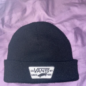 Svart  mössa från Vans - Snygg svart  mössa från Vans med ett broderat märke framtill. Perfekt för att hålla värmen under kyliga dagar. Köpt för 299kr