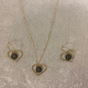 Guldhalsband och örhängen med hjärtan  - Elegant smyckesset med ett halsband och matchande örhängen i guld. Både halsbandet och örhängena har hjärtformade hängen med bokstäver inuti. Perfekt för att ge en personlig touch till din stil.  A-Z kvar , 139kr/set /paket , alla nya 