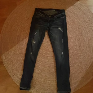 Mörkblå skinny jeans - Snygga mörkblå skinny jeans med låg midja och slitna detaljer. Perfekta på någon som är uppåt 170 cm. Tillverkade i denim.