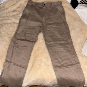 Beige linnebyxor från H&M - Snygga beige linnebyxor från H&M med straight fit. Perfekta för en avslappnad stil. Byxorna har en klassisk design med knapp och dragkedja framtill. Perfekta till våren och sommaren. I princip aldrig använda men vill bli av med dem därav billiga priset.