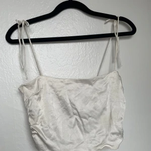 Vit ärmlös topp från Zara - Säljer en stilren vit topp från Zara med smala axelband och rynkade detaljer. 