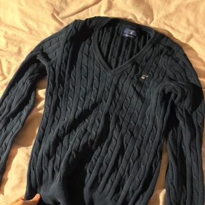 Tröja Gant - stilren mörkblå kabelstickad tröja från Gant med v-ringning.