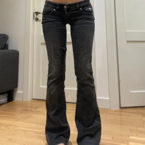 Svarta bootcut jeans - Snygga svarta bootcut jeans med väldigt låg midja. De har en klassisk femficksdesign och knappar fram. Perfekta för en stilren look.