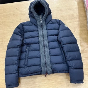 Mörkblå dunjacka från Moncler med inbyggd cardigan - Säljer en snygg mörkblå dunjacka från Moncler med dragkedja och huva. Jackan har en inbyggd cardigan på insidan som är riks fet. Strl 2 (M) men passar även S Vid en specifik och noggrann video, kom privat!