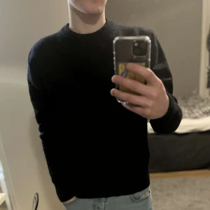Sweatshirt - Säljer en stilren svart tröja i ullblandning från Cubus. Tröjan har en klassisk rund halsringning och ribbade kanter. Perfekt för kyligare dagar. Storlek m men passar mer s