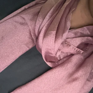 Rosa halsduk/ sjal med glittrig detalj - Snygg rosa halsduk/ sjal med glittriga detaljer längs kanterna. Perfekt för att ge en touch av glamour till din outfit. Mjuk och lätt att bära.