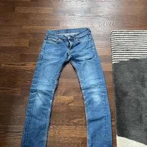 Blå jeans från Levi's - Säljer ett par klassiska blå Levi's jeans med fem fickor och knappgylf. De har en snygg tvätt och är perfekta för en avslappnad stil. Märkeslappen syns tydligt på baksidan. 511 slim fit storlek: 29:32