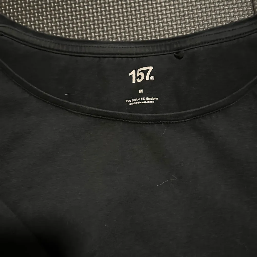 Säljer en stilren svart långärmad topp från 157. Tillverkad i en mjuk bomullsblandning med elastan för extra komfort. Perfekt för en enkel och snygg look.. Neuletakit & Villapaidat.