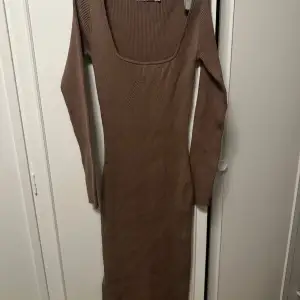 Snygg brun ribbad långklänning med långärmad design och fyrkantig urringning. Perfekt för en stilren och bekväm look.