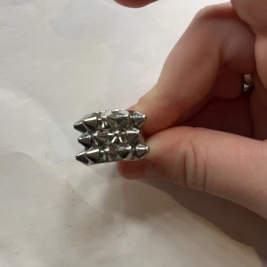 Silverfärgad ring med nitar från Edblad - Snygg och modern ring i silverfärg från Edblad. Ringen har ett coolt designmönster med nitar som ger en edgy look. Perfekt för att ge din outfit en extra touch av stil.