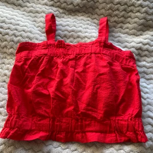 Röd topp barn - Säljer en söt röd linnetopp från H&M i samarbete med Liunic. Toppen har breda axelband och en elastisk midja. Perfekt för varma sommardagar! Skriv gärna innan köp 😊