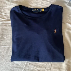 Mörkblå t-shirt från Ralph Lauren - Snygg mörkblå t-shirt från Ralph Lauren i bomull med broderad logga på bröstet. Den har en slim fit passform som ger en stilren look. Perfekt för en casual stil.Skick 8/10 nypris 1099 mitt pris 400