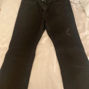 Svarta jeansbyxor - Snygga svarta jeansbyxor med en klassisk design. De har en rak passform och är perfekta för en stilren look. Byxorna har en knapp och dragkedja framtill samt fickor både fram och bak.