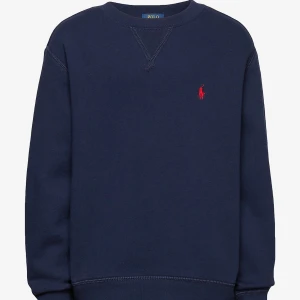 Mörkblå sweatshirt från Polo Ralph Lauren - Säljer en stilren mörkblå sweatshirt från Polo Ralph Lauren med det klassiska röda logotypbroderiet på bröstet. Tröjan har långa ärmar och ribbade muddar vid ärmslut och nederkant. Perfekt för en avslappnad look. Liten fläck i ärmen, mudden 