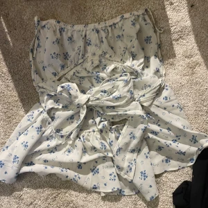 Söt blus  - Vit blus/linne med blått blommönster, vet ej märket, köpt på plick men fortfarande nyskick!! Knytbar där bak, storlek s. Kontakta vid frågor eller för bilder när den sitter på, kontakta innan köp💓💓tyvärr endast swish då mitt bankid inte går att koppla till plick så jag får ej mina pengar annars…