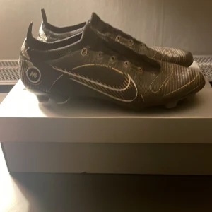  Fotbollskor - Snygga svarta fotbollsskor från Nike med vita detaljer och snörning. Skorna har en modern design med en tydlig Nike-logga på sidan. Perfekta för fotbollsplanen med sin slitstarka konstruktion.