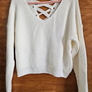 Miss Selfridge Off white lace back - Säljer en snygg vit stickad tröja med unik snörning i ryggen. Tröjan har en v-ringad design och långa ärmar, perfekt för en stilren look. Passar utmärkt till både jeans och kjol. Perfekt för kyligare dagar! Akryl 100 % Aldrig använd!