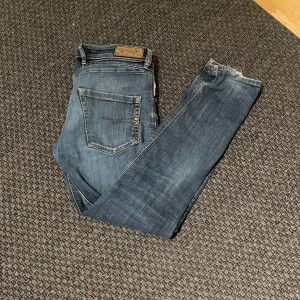Diesel selvedge jeans - Snygga blå jeans från Diesel med slitna detaler och en riktigt fet slitning på ena benet. Perfekta för en avslappnad stil. Klassisk femficksdesign och knappgylf.