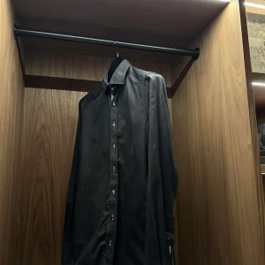 Svart skjorta från Stenströms - Elegant svart skjorta från Stenströms. Skjortan har långa ärmar och knappar framtill. Kragen har ett diskret mönster på insidan som ger en stilren touch.