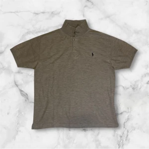 Beige pikétröja från Polo Ralph Lauren - Säljer en stilren beige pikétröja från Polo Ralph Lauren. Tröjan har korta ärmar och en klassisk krage med knappar. Den är dekorerad med det ikoniska broderade logotypen på bröstet. Perfekt för en avslappnad men ändå elegant look. Storleken är xl men passar också L