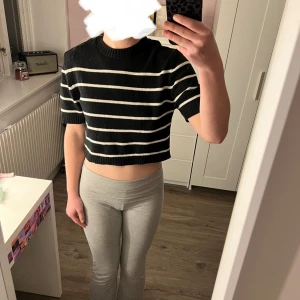 Randig stickad tröja - Säljer en svart och vit randig stickad tröja med korta ärmar. Perfekt för en stilren och avslappnad look. Tröjan har en rund halsringning och är gjord i ett mjukt material.