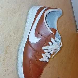 Bruna Nike Air Force 1 sneakers - Snygga bruna Nike Air Force sneakers med vit sula och vit swoosh. Storlek 42 nyligt skick och har bara använts en eller två gånger 