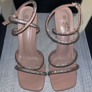 Rosa/Beige sandaler med glittriga remmar - Eleganta rosa/beige sandaler köpta i Stockholm (Yes London)  med glittriga remmar och en smal klack. Sandalerna har en fyrkantig tå och justerbar rem runt ankeln. Helt nya endast testade, Storlek 36! ✨