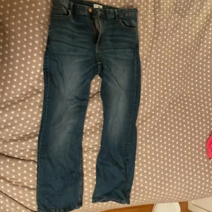 Blå jeans från Lindex - Säljer ett par klassiska blå jeans från Lindex i modellen Karen. De har en rak passform och är tillverkade i ett slitstarkt denimtyg. Perfekta för en avslappnad stil.