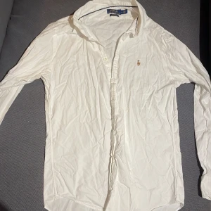 Vit skjorta från Polo Ralph Lauren - Säljer en stilren vit skjorta från Polo Ralph Lauren i slim fit. Skjortan är tillverkad i 100% bomull och har en broderad logotyp på bröstet. Perfekt för en klassisk look.