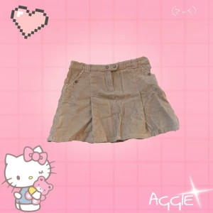 Beige manchesterkjol från H&M L.O.G.G. - Säljer en snygg manchesterkjol från H&M L.O.G.G. Kjolen har en kort längd med två knappar fram och fickor både fram och bak. Den är soft ribbad men det syns inte på långt håll (se sista bilden). Köpt tidigt 2000 talet. På bilderna så ser den mer brun ut men i verkligheten är den mer grön-naturaktig.