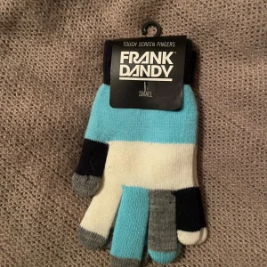 Flerfärgade touchscreen-vantar från Frank Dandy - Touchscreen-handskar från Frank Dandy. I storlek small och med flera färger: blå, vit, svart och grå. Perfekta för att hålla händerna varma samtidigt som du kan använda din smartphone. Helt nya och oanvända!