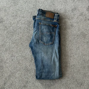 Blå jeans från Nudie Jeans - Säljer ett par snygga blå jeans från Nudie Jeans. De har en klassisk femficksdesign och är i en skön denimkvalitet. Perfekta för både vardag och fest! 🕺