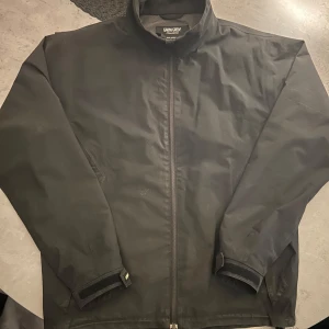 Svart vindjacka från Galvin Green - Säljer en svart vindjacka från Galvin Green i storlek M. Jackan är tillverkad i GORE-TEX-material som ger fullständigt skydd mot vind och regn. Den har en dragkedja framtill och långa ärmar. Perfekt för blåsiga och regniga dagar!