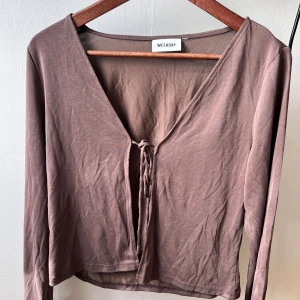 Brun långärmad topp från Weekday - Säljer en snygg brun långärmad kofta från Weekday. Den har en v-ringad design med knytning framtill. inga defekter mycket bra skick 