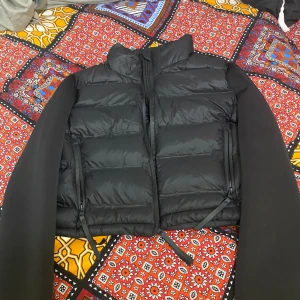 Svart pufferjacka från Zara - Säljer en snygg svart pufferjacka från Zara i storlek XS. Jackan har en stilren design med dragkedja och är perfekt för kyliga dagar. Den är i bra skick och passar både till vardags och fest. Ett måste i garderoben för våren 