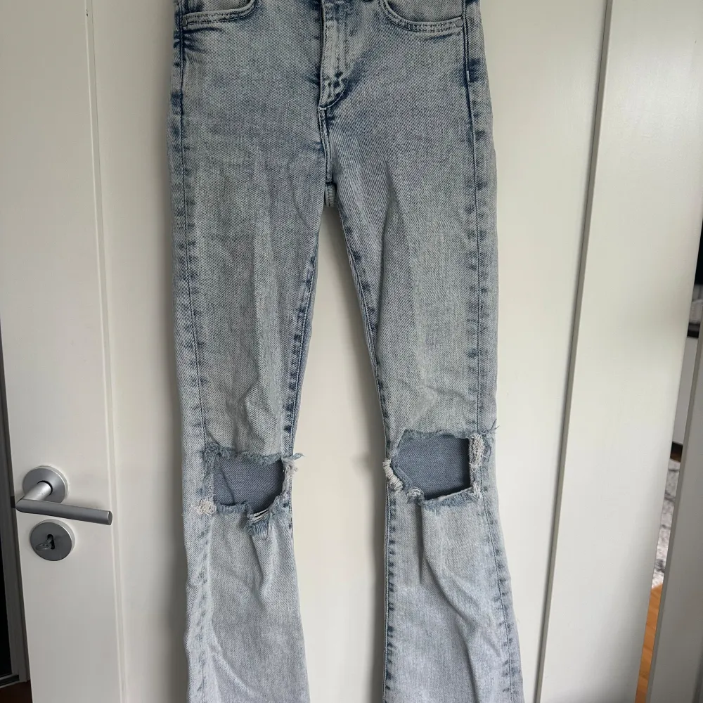 Ljusblåa Bootcut jeans i storlek xs med hål på knäna från bikbok. I bra skick.. Jeans & Byxor.