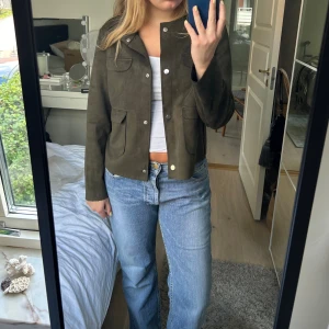 Grön mocka jacka - Mörkgrön jacka men mocka liknande material och med knappar och fickor, storlek 42 men sitter så som på bilden på mig som brukar ha 36/38