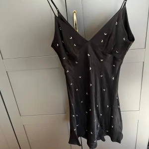Svart klänning - Jag säljer en jättesnygg svart klänning med silvriga detaljer och justerbara band. Säljer då klänningen tyvärr inte passar mig längre. Köpt på zara.